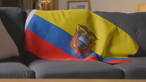 Close Up Of Flag Of Ecuador Draped Over Sofa At Home With Football Ready For Match On TV 1