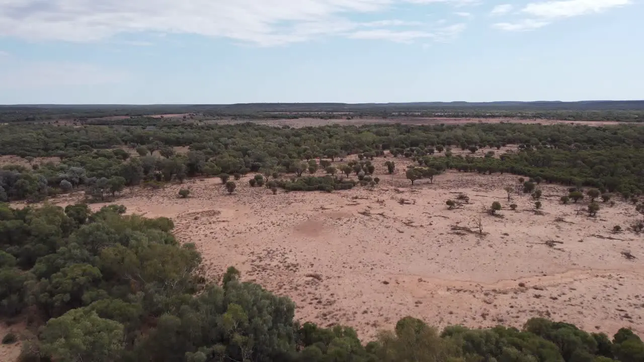 Drone flying over a remote Australian outback land with trees and some bold patches