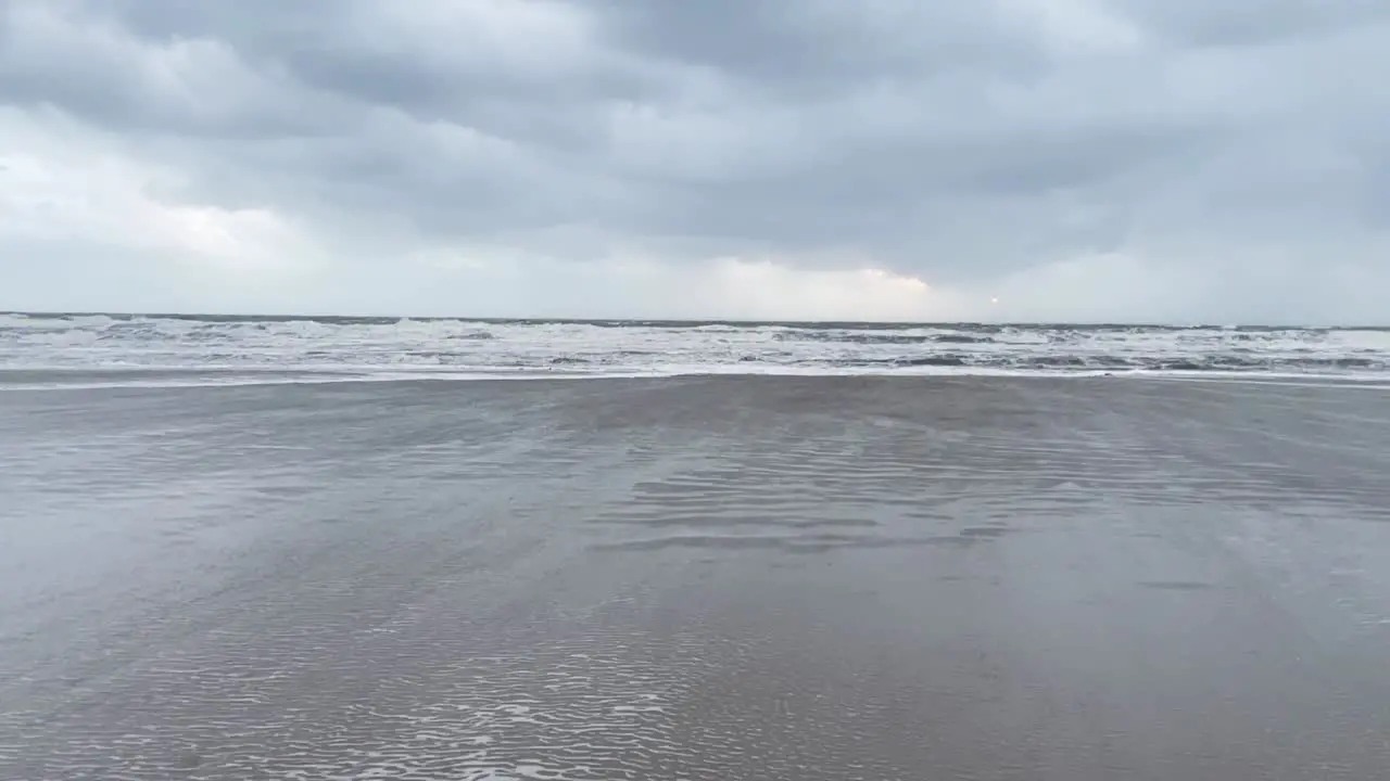 Wide shot of wind hitting the beach creating ripples in the water