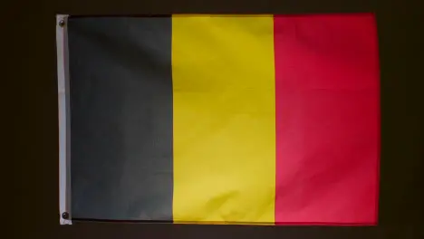 Studio Shot Of Flag Of Belgium Falling Down Against Black Background