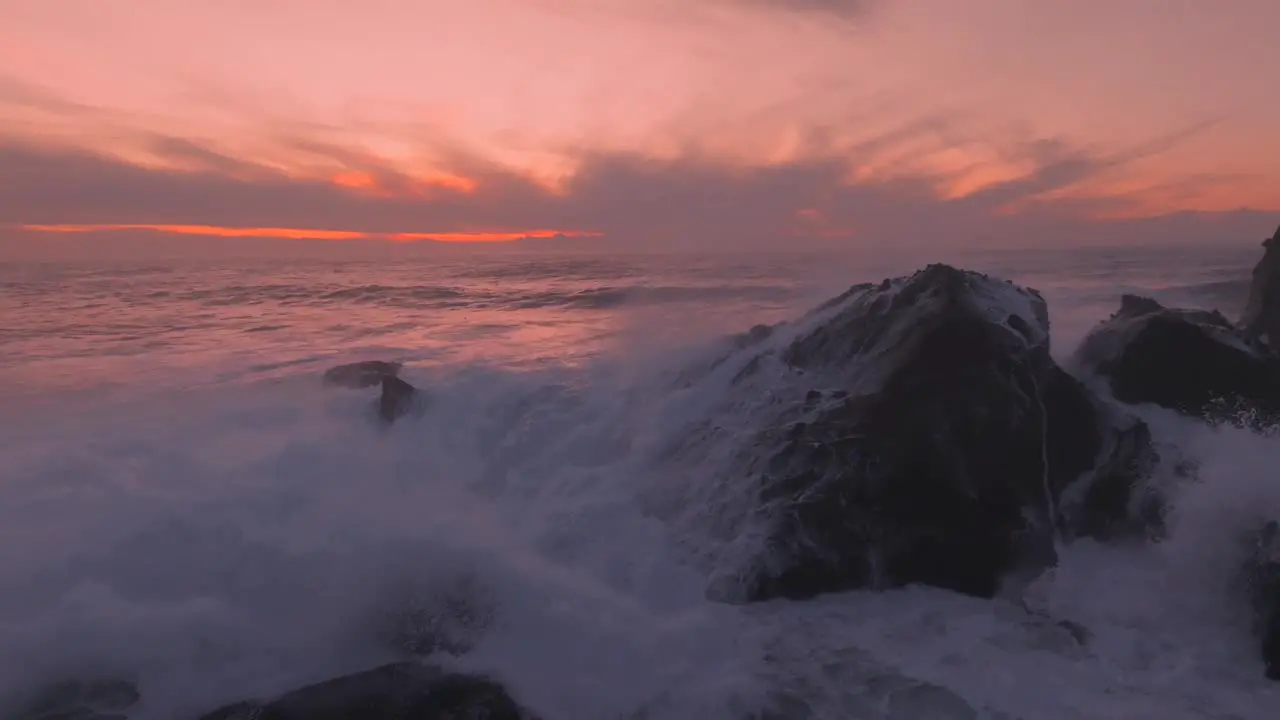 Vivid colors of the sunset with some fierce waves crashing on rocks