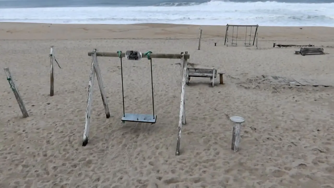 Wooden structures and swings at Costa Nova Beach on a cloudy day with turbulent sea conditions