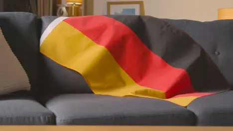 Close Up Of Flag Of Germany Draped Over Sofa At Home Ready For Match On TV 1