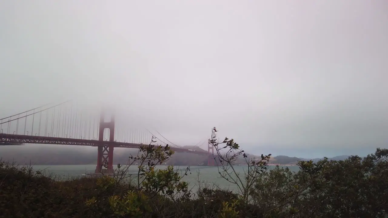 Gimbal shot panning to the Golden Gate Bridge enveloped in fog from the Presidio of San Francisco California