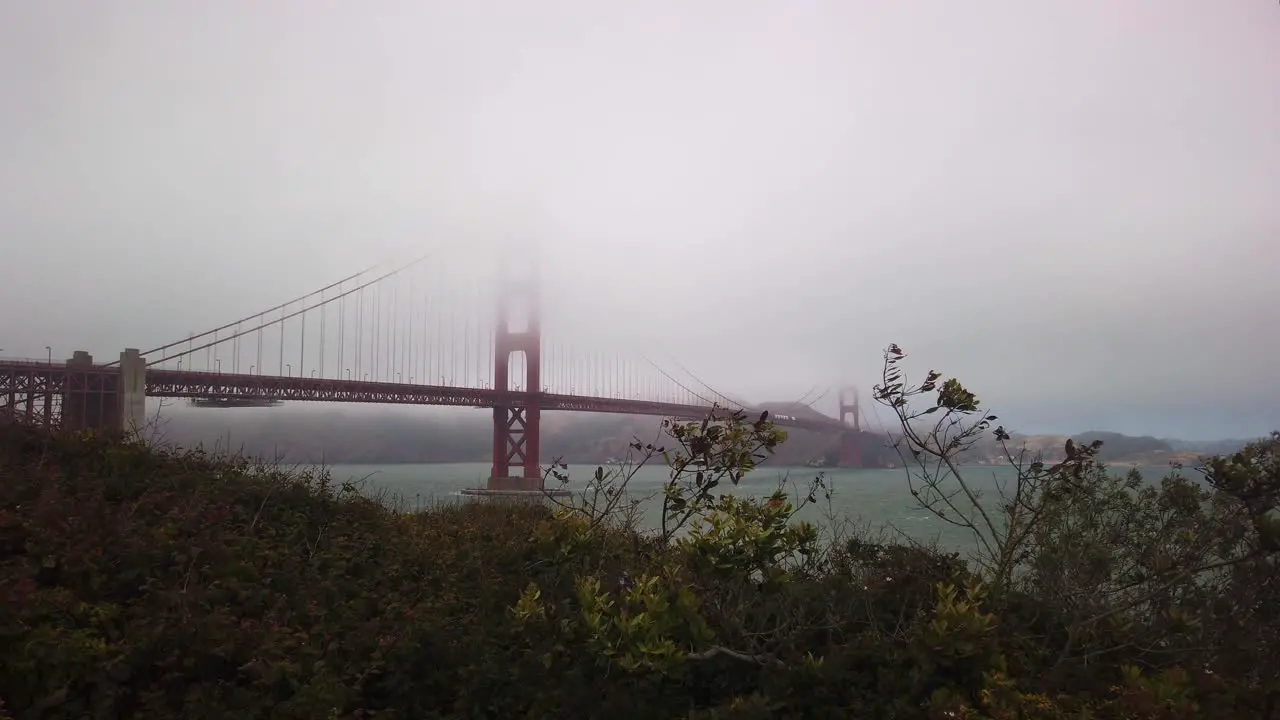 Gimbal wide static shot of the Golden Gate Bridge covered in fog from the Presidio in San Francisco California