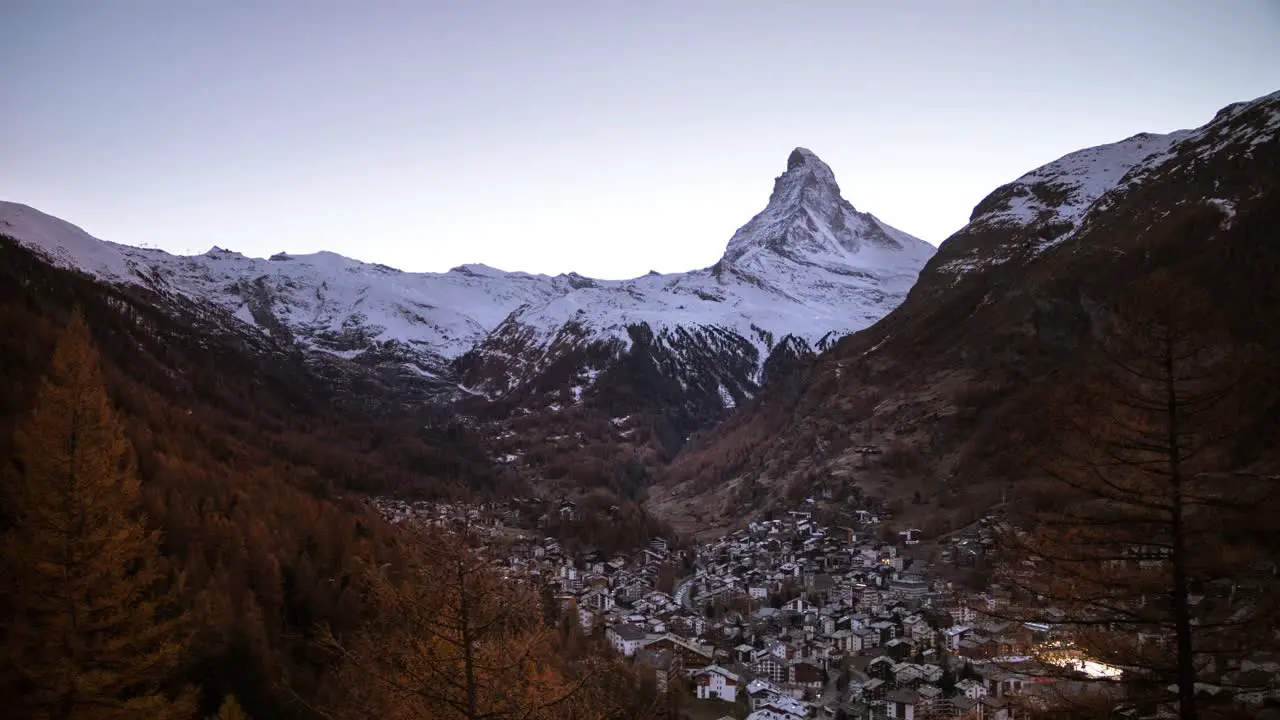 Day to night timelapse of the Matterhorn as seen from Zermatt Switzerland as the stars light up the sky along with the city lights