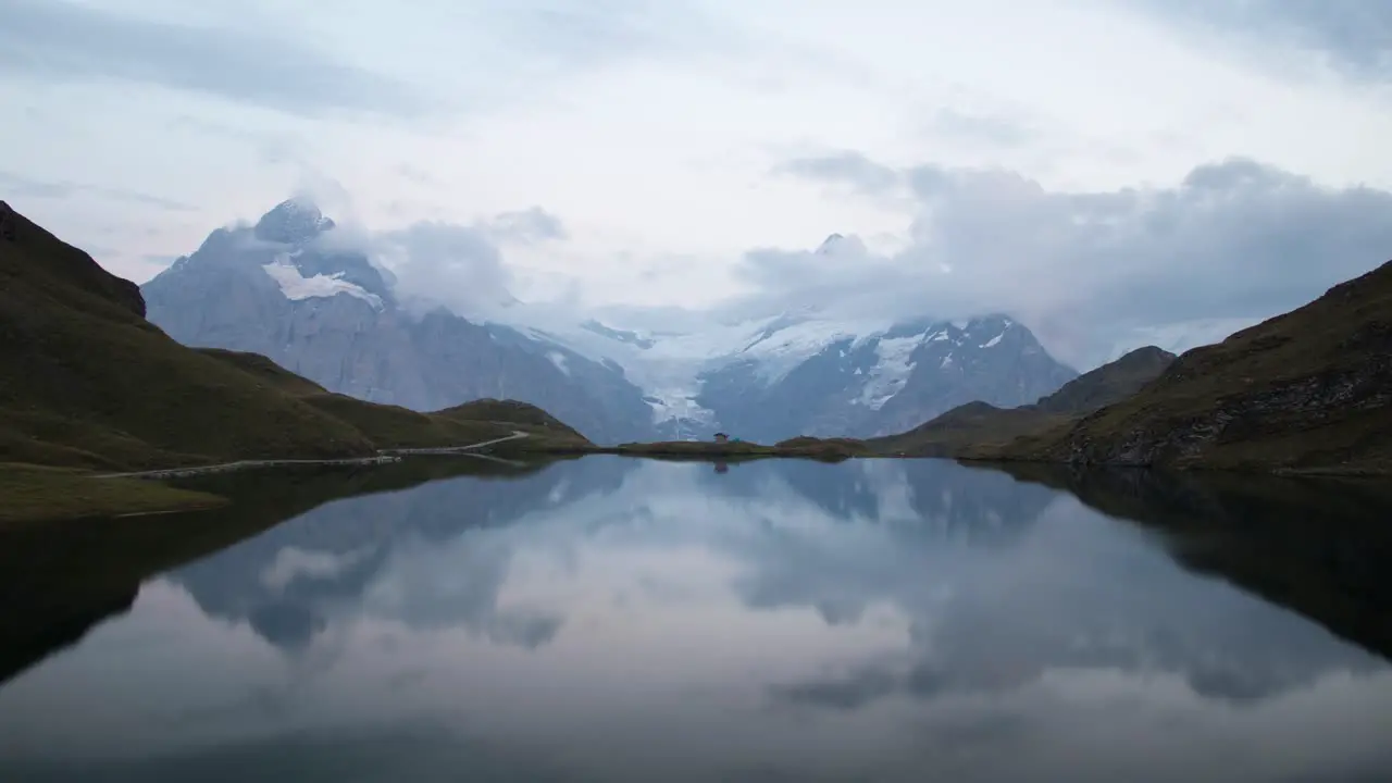 Day to night timelapse of lake Bachalpsee in Grindelwald Switzerland with a view of alpine peaks glaciers and stars reflected on the lake's surface