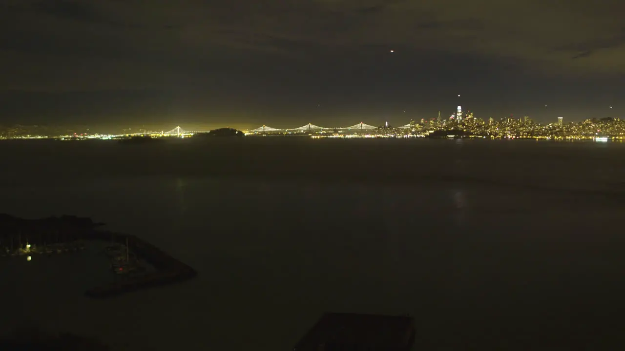 Time lapse of downtown San Fransisco from over the waters of the Pacific Ocean with the Oakland Bay Bridge in the background located in California