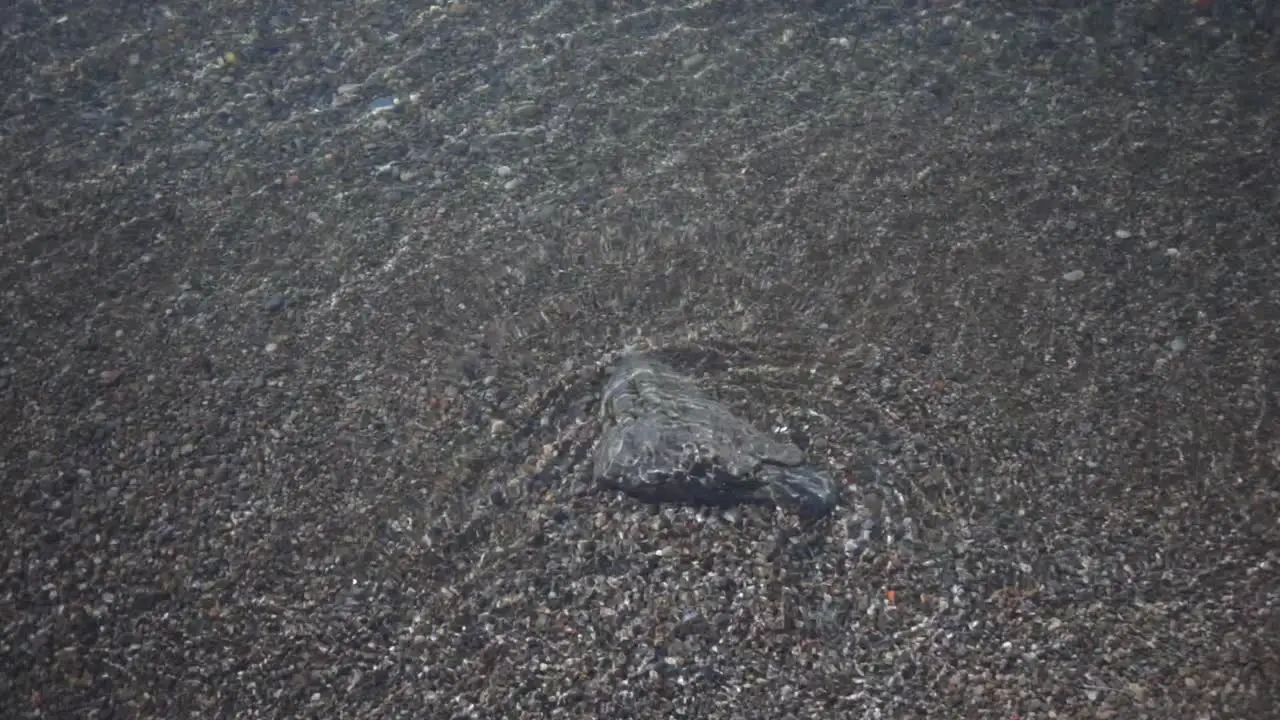 Crystal Clear Sea Water Rippling Over The Small Rock On The Sand By The Shore In Toronto Canada Closeup Shot