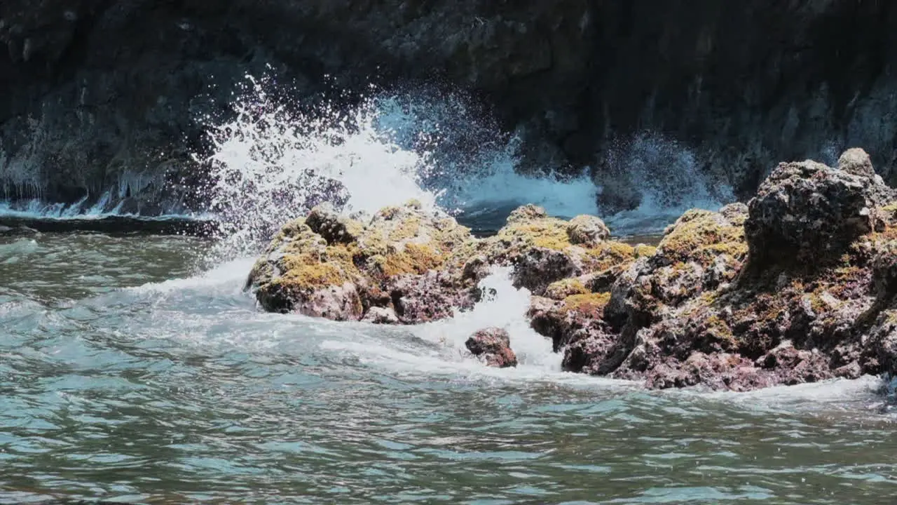 Slow motion static clip of ocean waves crashing against rocky Hawaiian coast