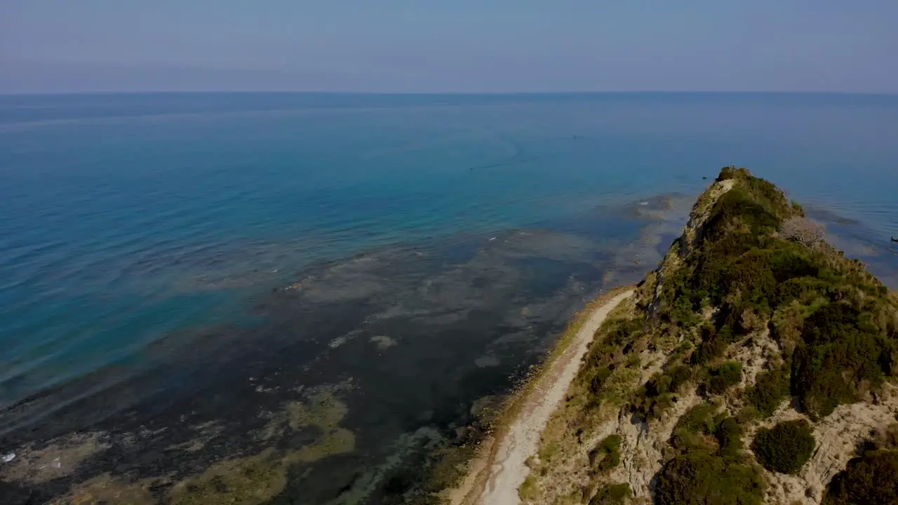 Polluted sea water with algae around green hill of cape in Mediterranean seaside