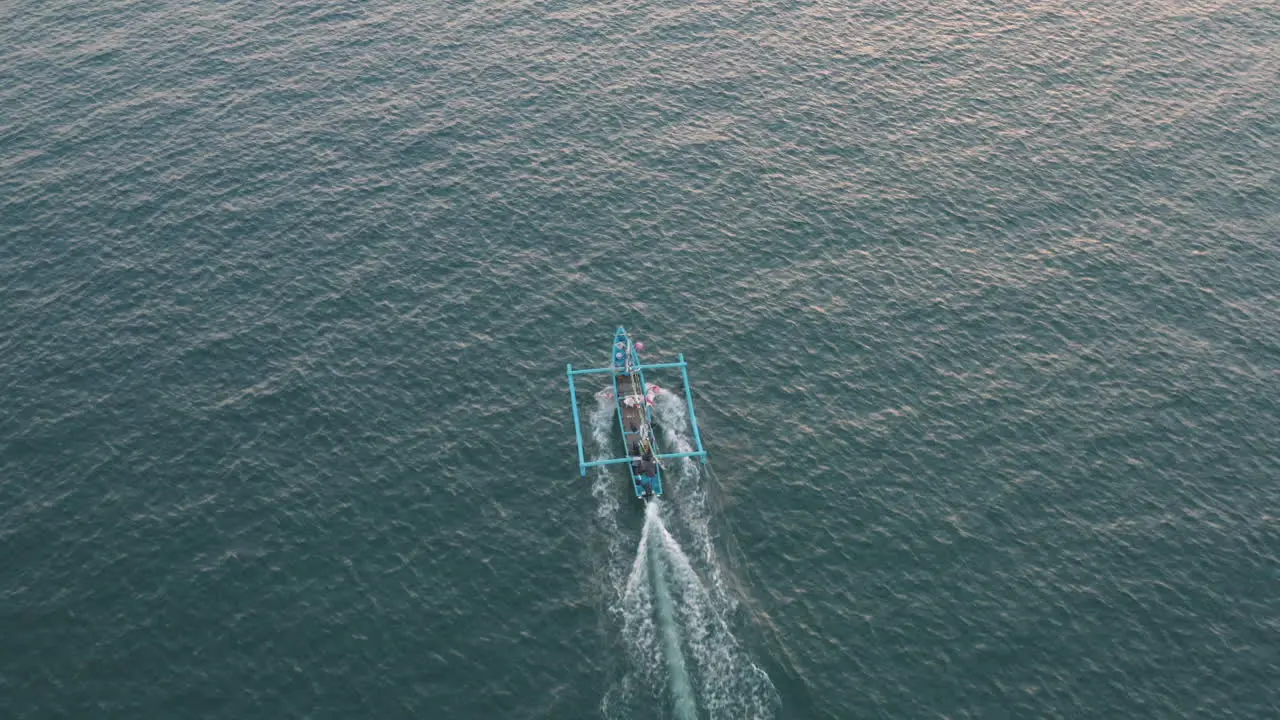 Tracking above and behind a local tour boat as it motors across open water off the coast of Bali aerial