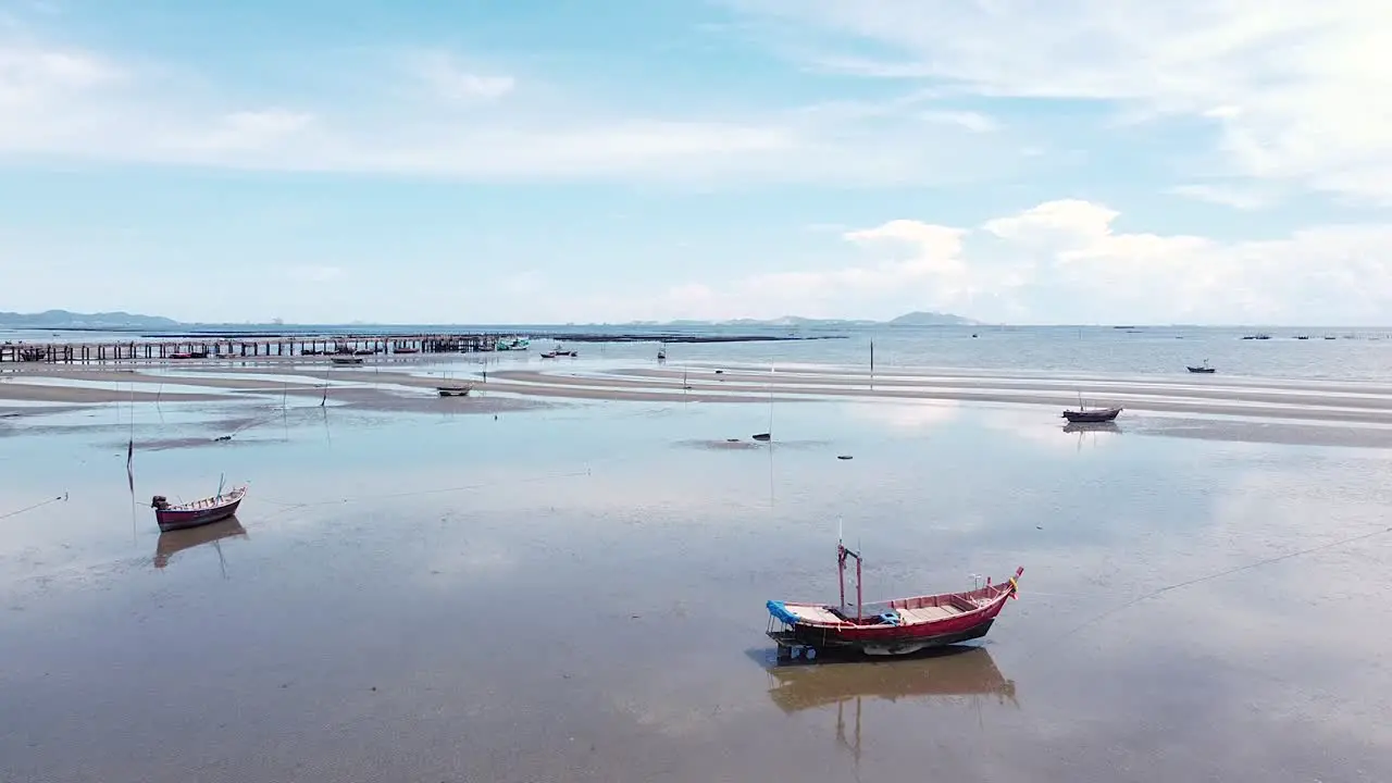 Traditional fishing boats sitting quietly on the sandy beach during low tide in Thailand low aerial