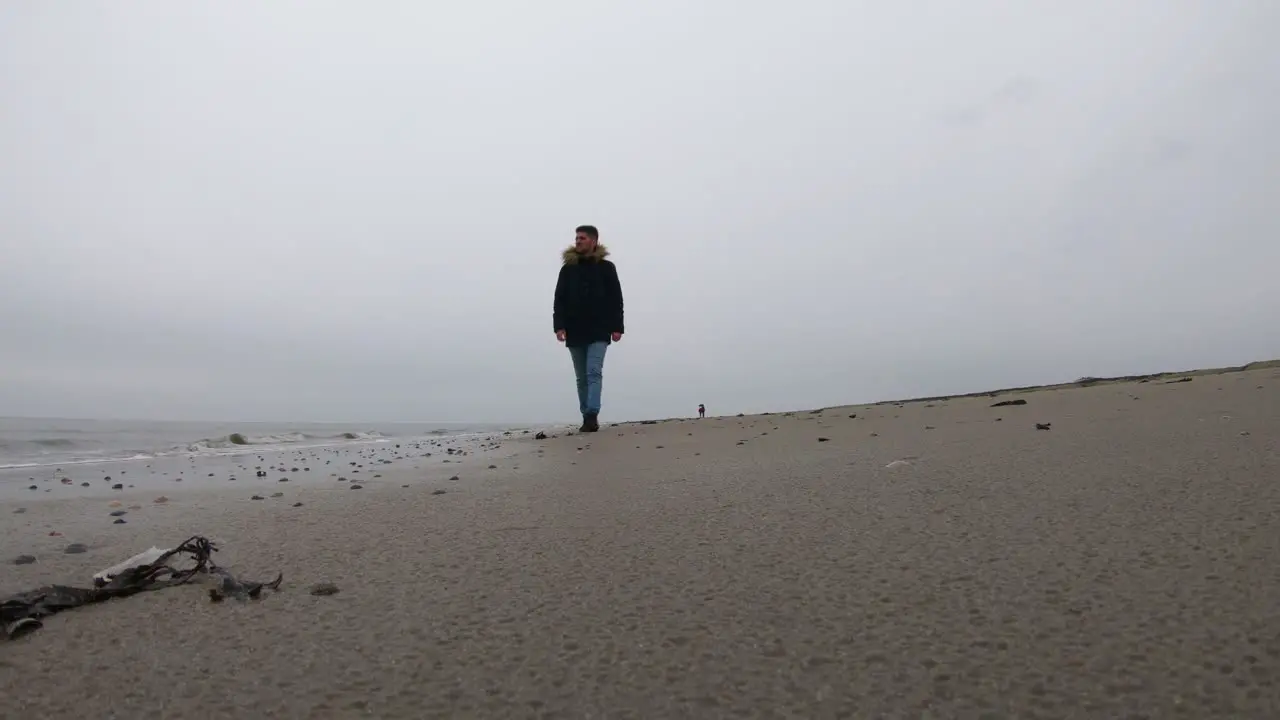 Man walking alone on the beach on a rainy day