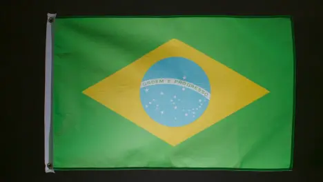 Studio Shot Of Flag Of Brazil Falling Down Against Black Background