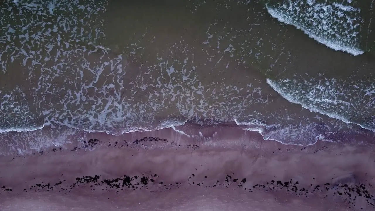 Beautiful aerial view of an old wooden pier at the Baltic sea coastline overcast day white sand beach affected by sea coastal erosion calm seashore wide birdseye drone dolly shot moving right