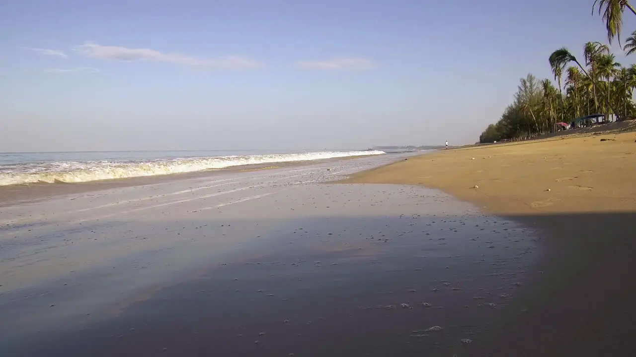 Low angle of beautiful tropical waves and man jogging on beach at morning sunrise