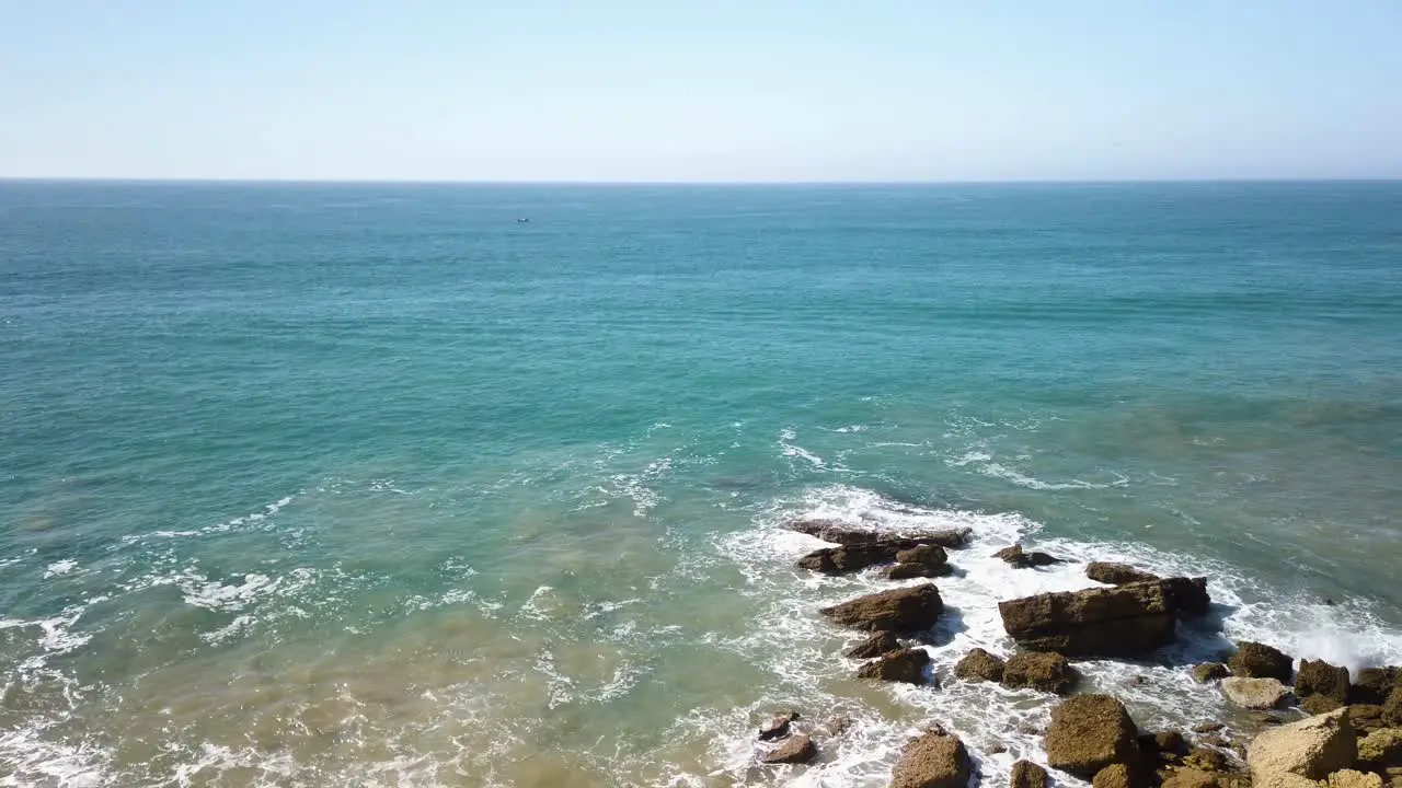 Blue Ocean Waves Lapping Against Large Rocks with Copy Space on Left