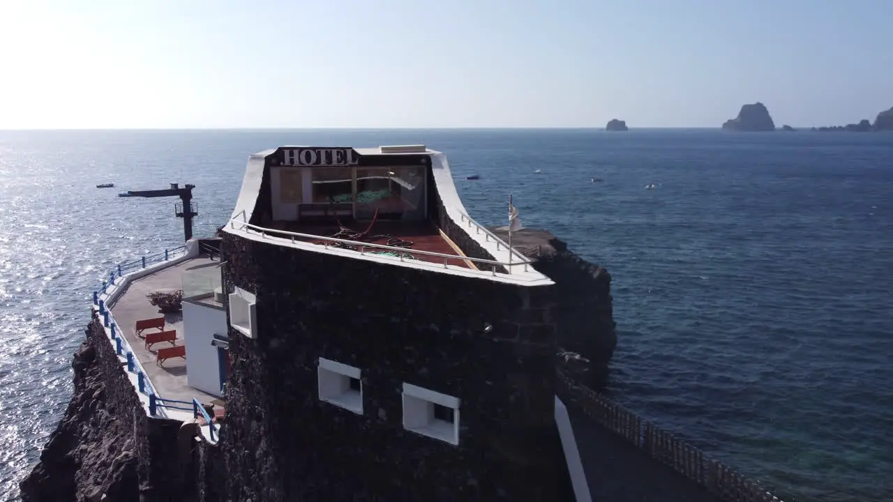 A small hotel Puntagrande overlooking the calm sea on a rocky plateau of lava origin in sunny and windy weather El Hierro drone shot