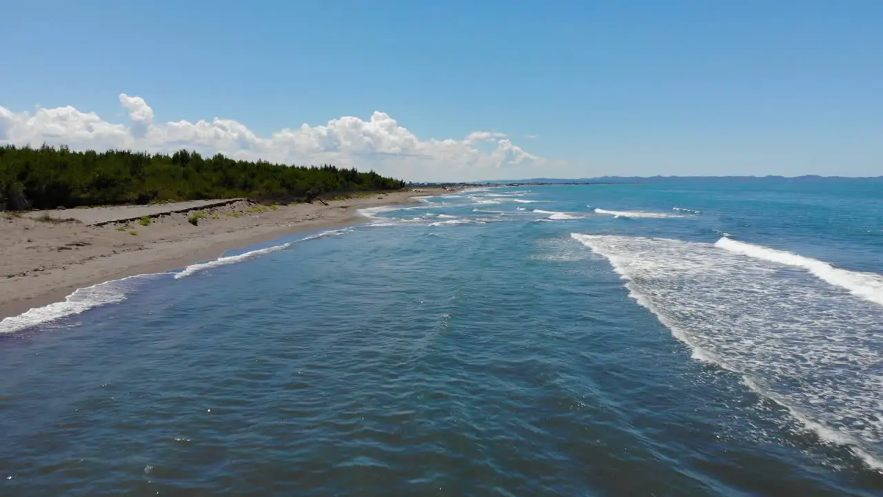 Seaside with white waves splashing on unspoiled sandy beach on a sunny day in Adriatic coast aerial view