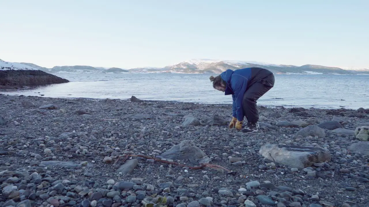 Man Picking Up Rocks By The River During His Camping Trip In Indre Fosen Norway