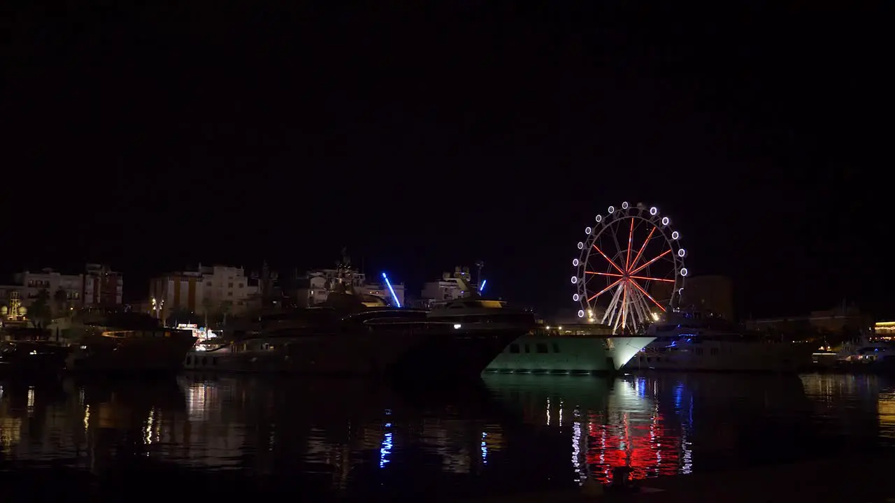 Ferris wheel next to yachts in Barcelona at night