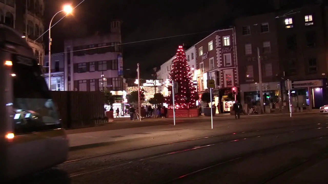 Still shot of the Luas tram passing by and Christmas tree on Graton St with people flocking around it