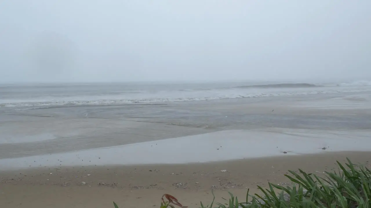 Dark Rainy Day on Sandy Beach During Monsoon Season Ahead of Tropical Storm Waves Breaking on Shore