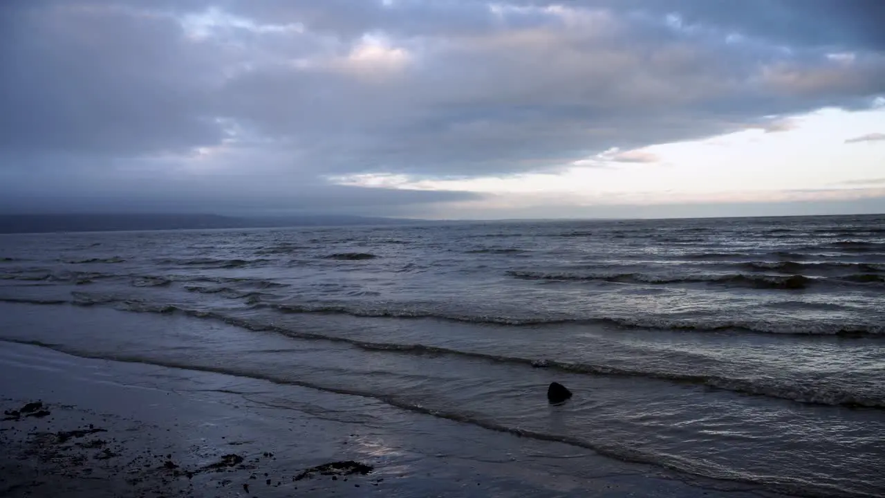 Waves splash into the sandy beach  cloudy weather and white clouds in the sky  static