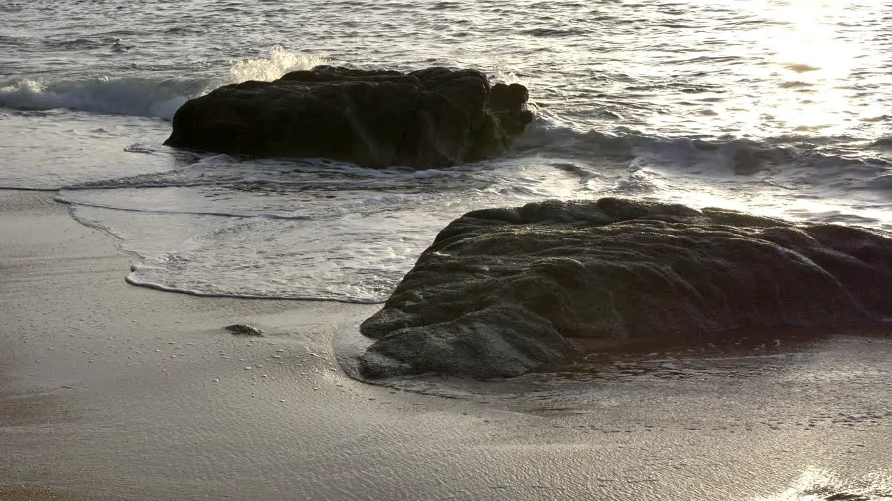 High angle shot detail of two rocks on the beach the sea waves motion during sunset