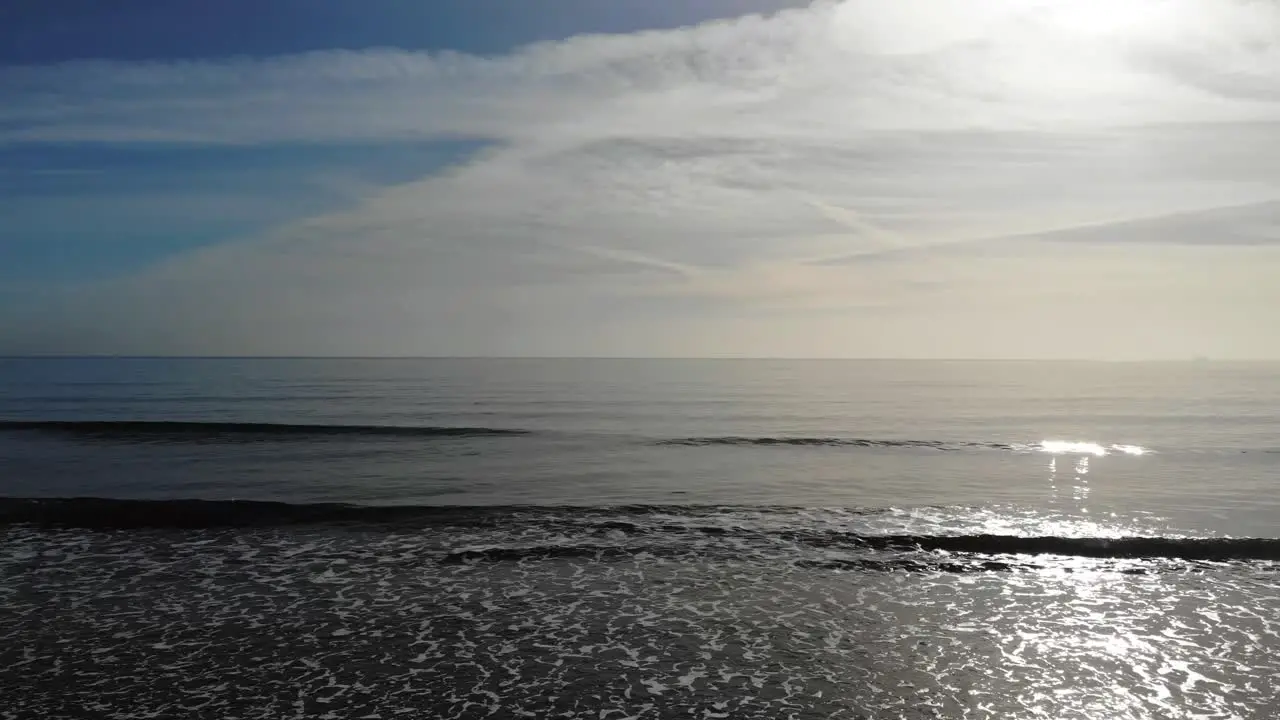 Stationary shot of gentle waves rolling onto a beach on a beautiful sunny day