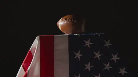 Low Key Lighting Studio Shot Of American Football On Stars And Stripes Flag 8