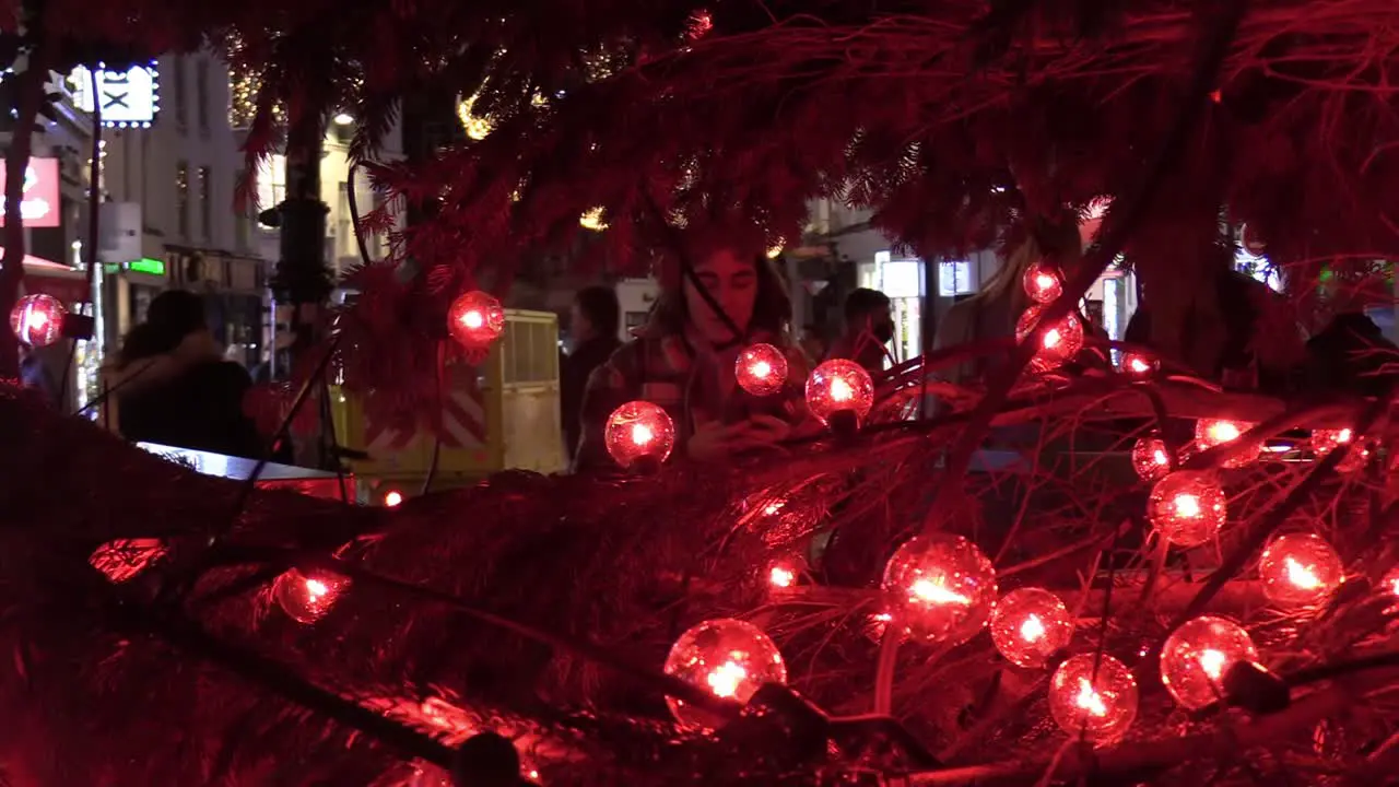 Zooming in on a person taking photos at a Christmas tree on Grafton St with lights around her and people in the background