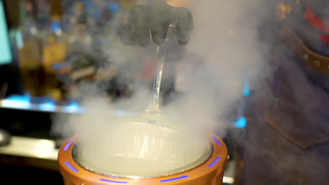 Bartender cooling a glass with an ice machine in a bar