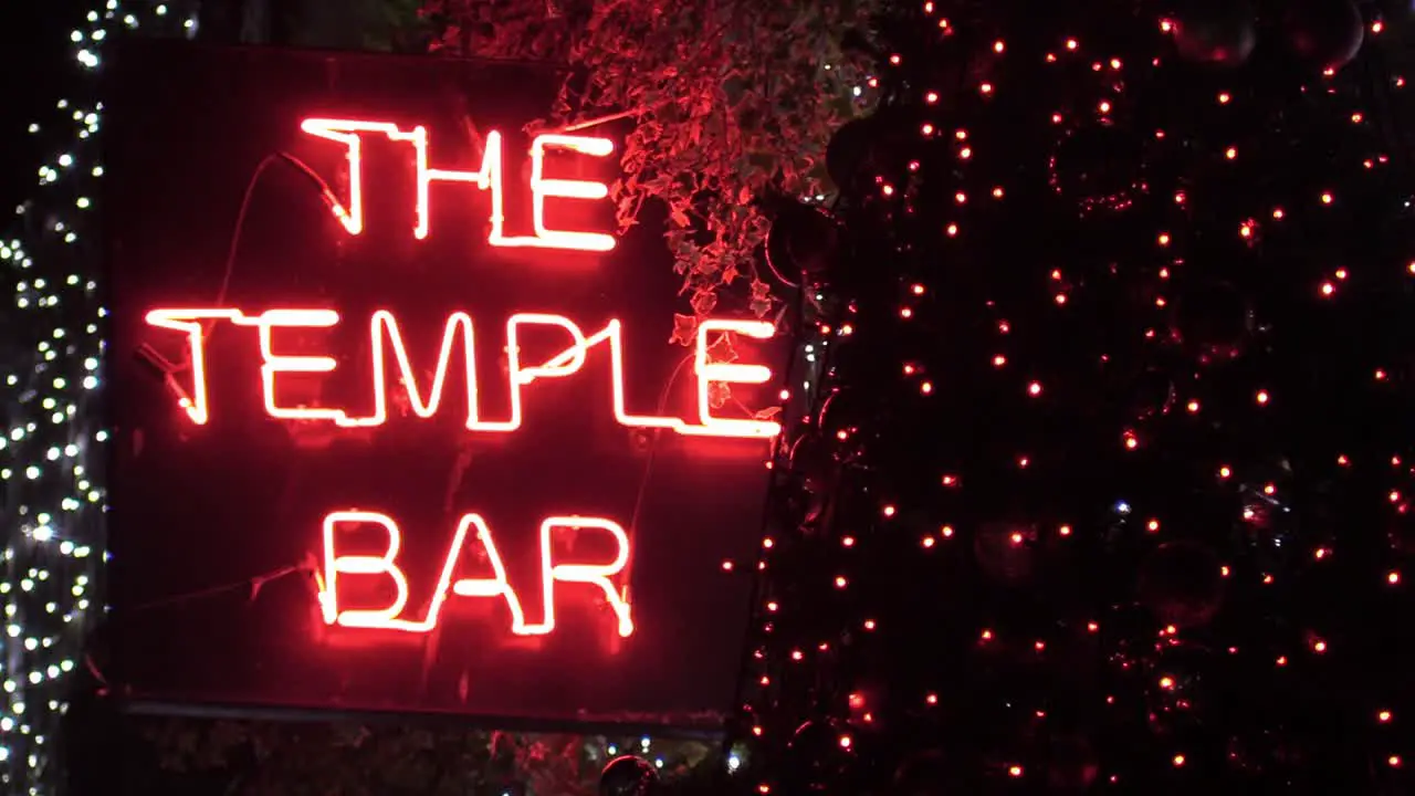 Still shot of a bar singe in red neon lights with some Christmas decorations around it