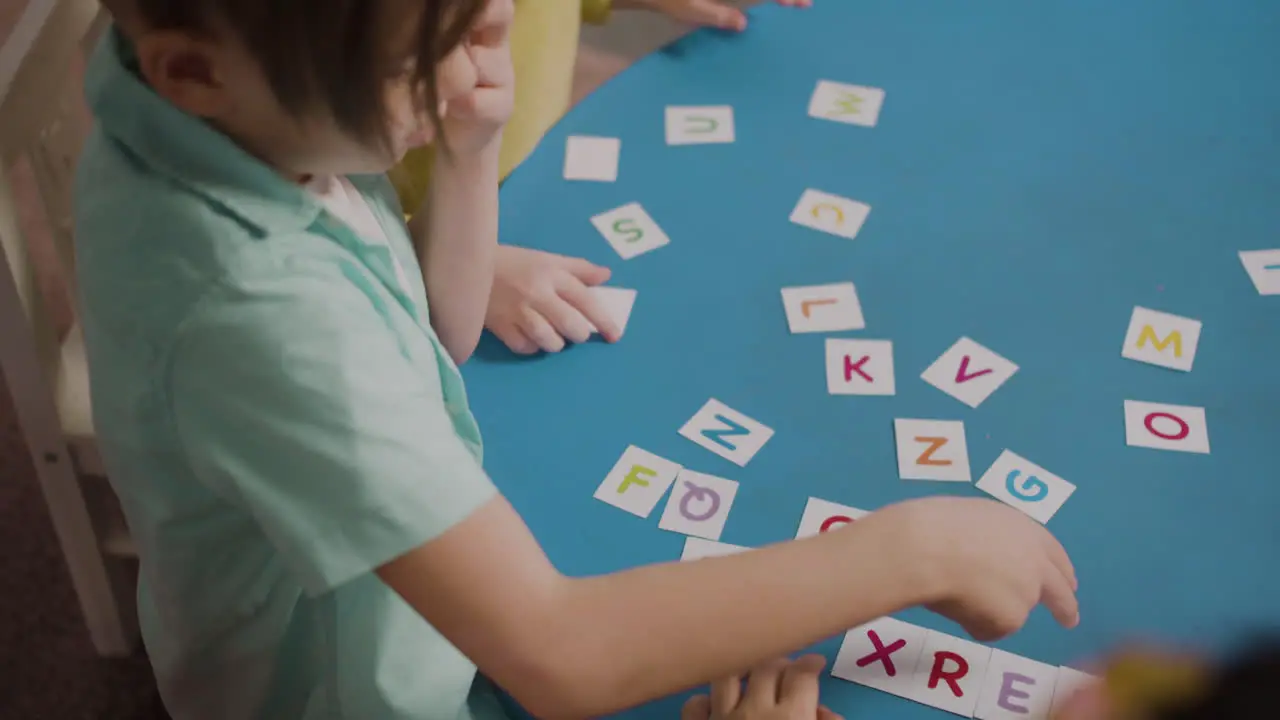 Primer Plano De Los Alumnos Sentados En El Escritorio Redondo Y Jugando Con Las Letras Del Alfabeto En Una Escuela Montessori 1