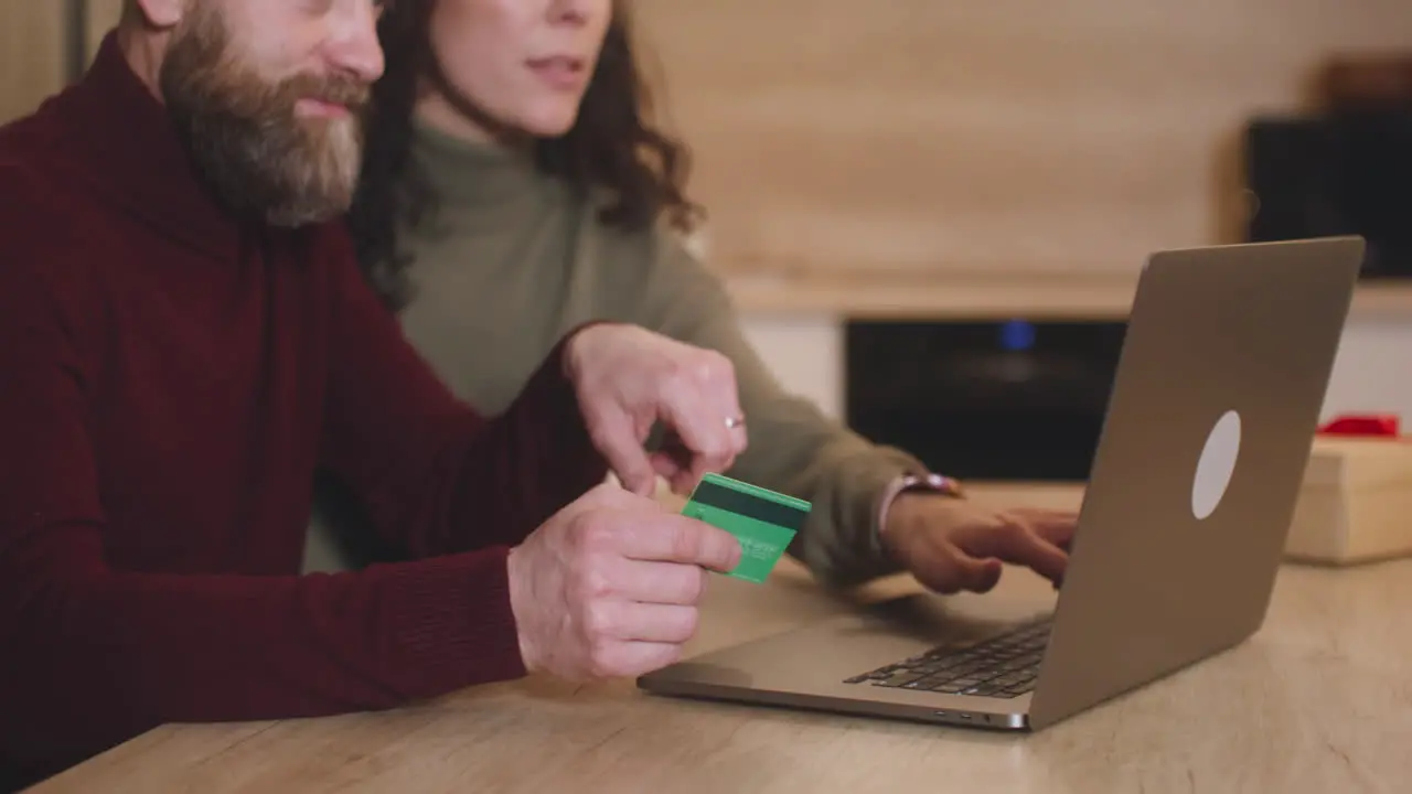 Pareja Comprando En Línea Con Una Tarjeta De Crédito Usando Una Computadora Portátil Sentada En Una Mesa Cerca De Un Regalo