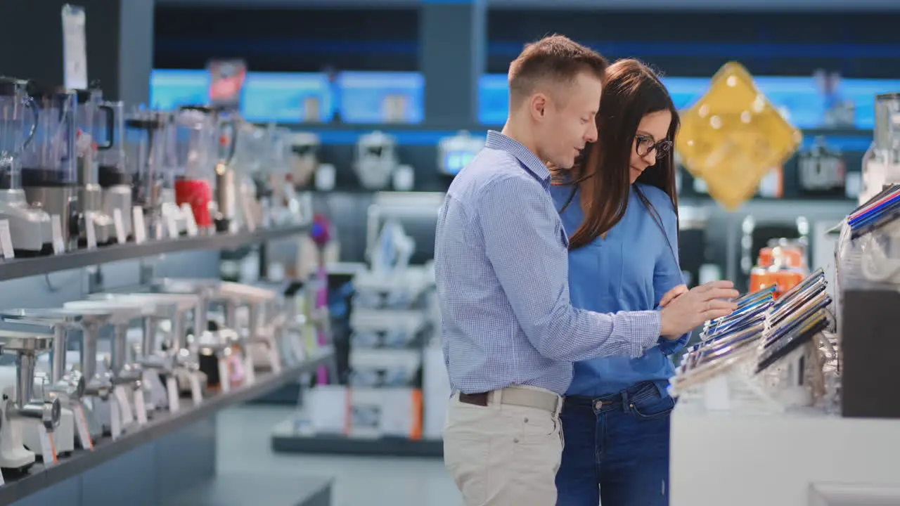 Feliz Pareja Familiar Hombre Y Mujer Parados En El Mostrador Con Teléfonos Móviles Vestidos Con Ropa Informal Eligiendo Un Nuevo Teléfono Inteligente En Una Tienda De Electrónica Moderna