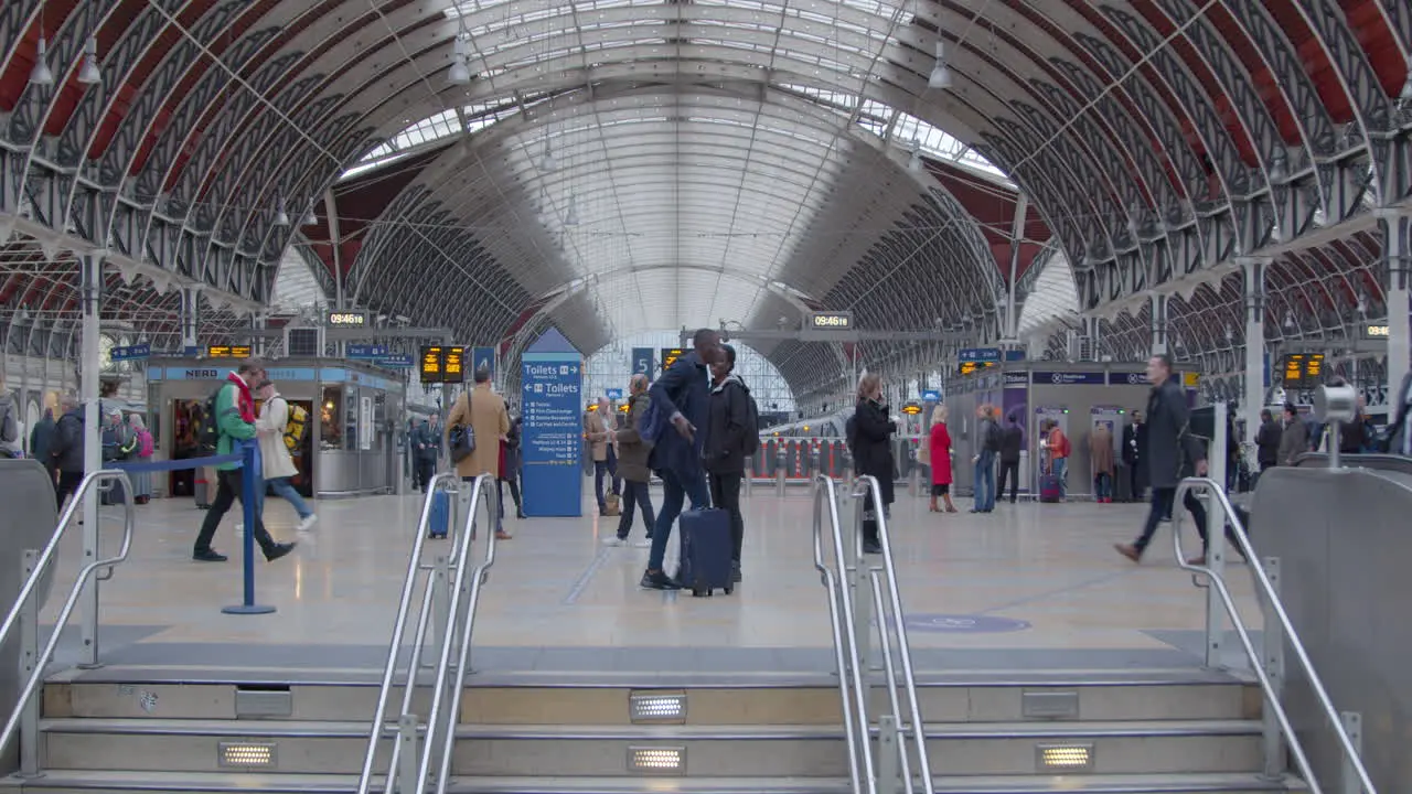 Two people talk at top of stairs in train station