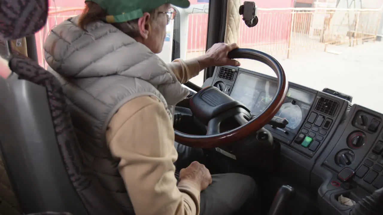 Rückansicht Eines älteren Arbeiters Mit Mütze Und Weste Der Einen LKW In Einem Logistikpark Fährt