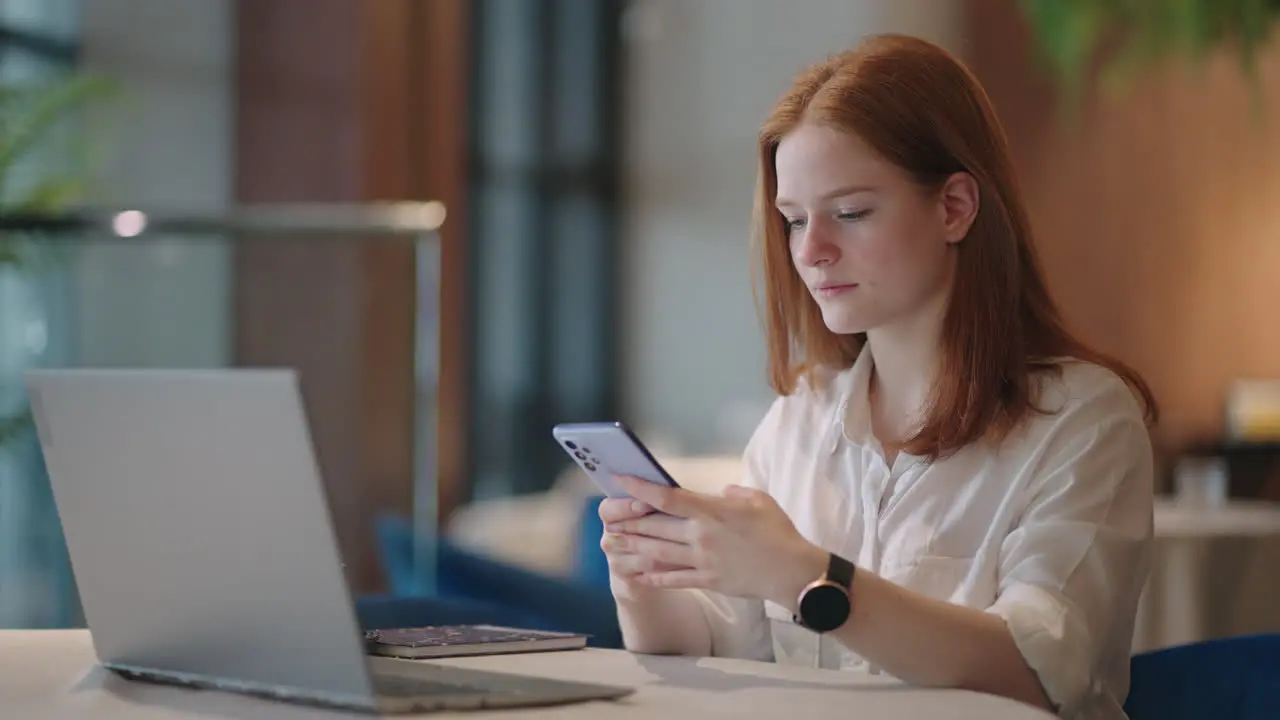 Una Mujer Joven Está Usando Un Teléfono Inteligente Para Chatear En Línea En Una Aplicación Durante La Jornada Laboral En La Oficina