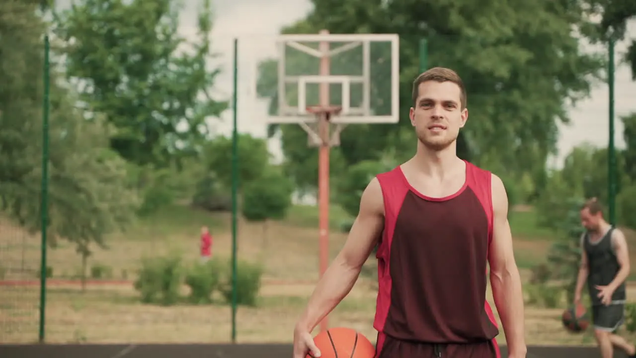 Im Vordergrund Ein Gutaussehender Basketballspieler Mit Ball Der Nach Einer Guten Produktiven Trainingseinheit Schwer Atmet Während Er In Die Kamera Schaut Und Selbstbewusst Lächelt