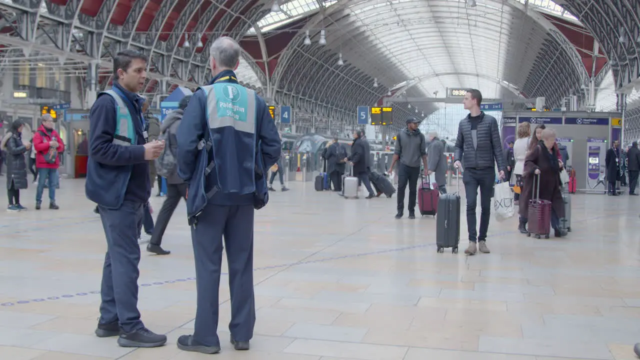 Two train stewards stands as people pass through station