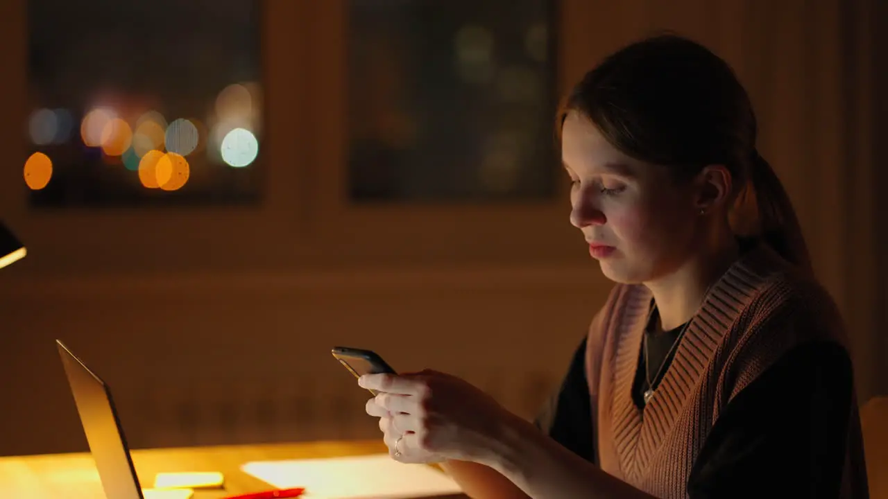 Beautiful woman working late at home using a laptop and receiving text messages on smartphone Hands of woman texting message on mobile smart phone for communication and chatting on social online