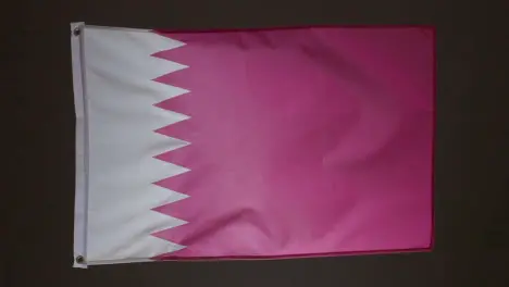 Studio Shot Of Flag Of Qatar Flying Against Black Background