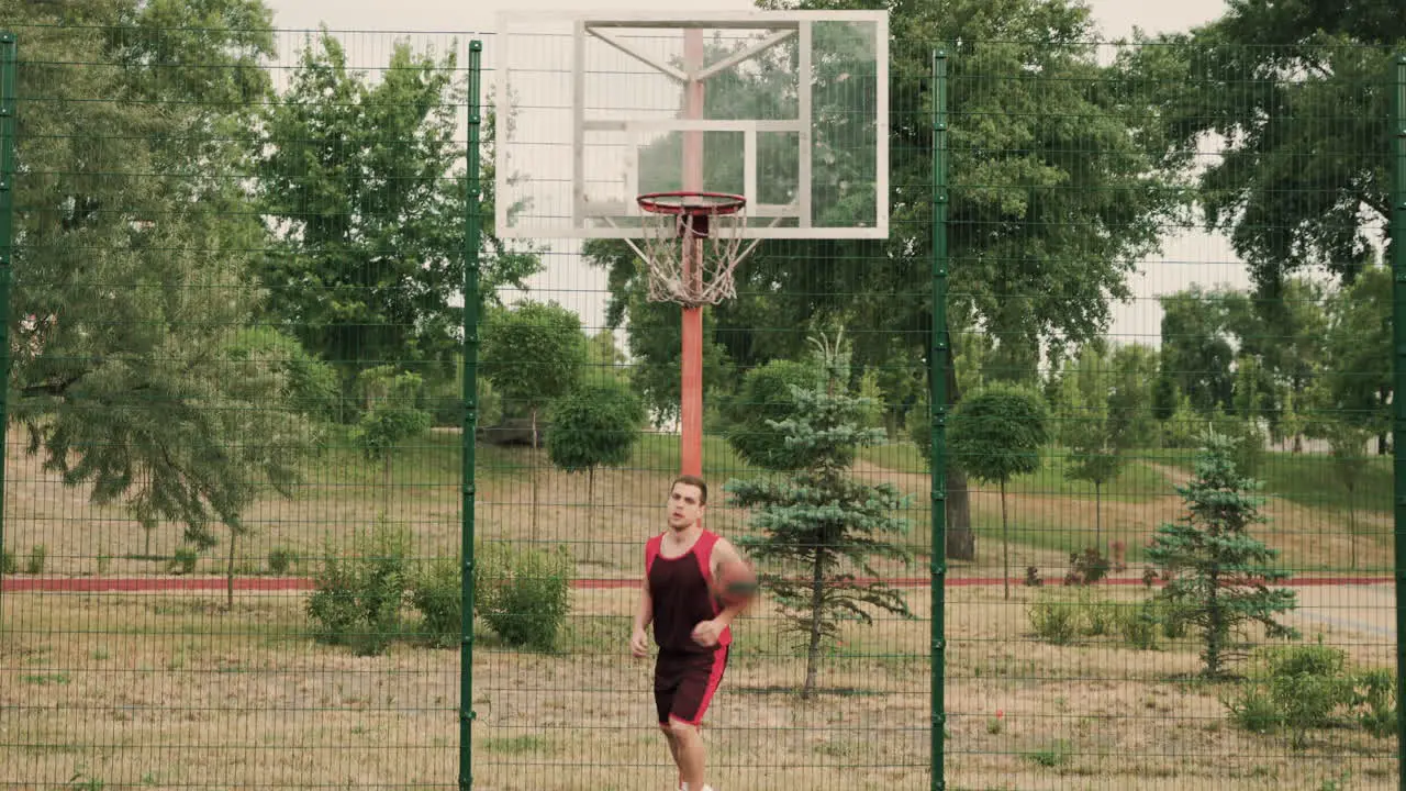 Male Basketball Player Dribbling And Throwing Ball Into Basket During His Training Session In An Outdoor Basketball Court