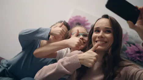 Family selfie photo on mobile phone Happy mother with kids showing thumbs up