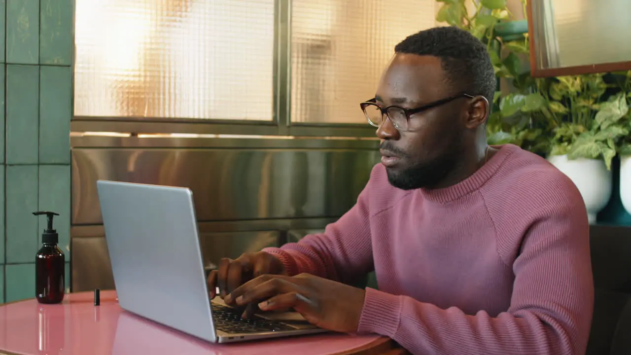 African American Man Typing on Laptop in Cafe