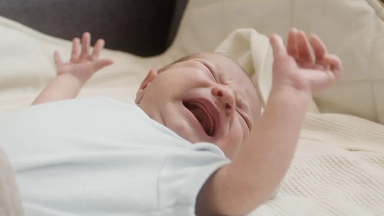 Close Up Of A Cute Newborn Baby Lying On Bed And Crying 1