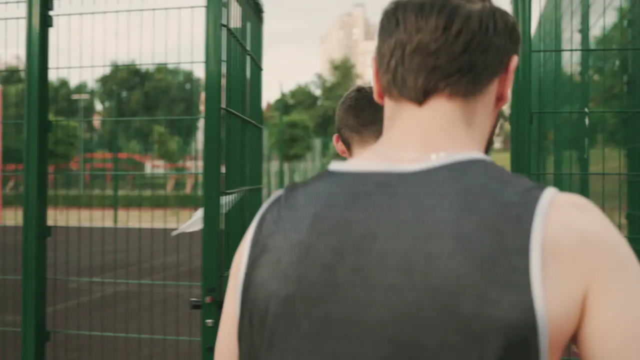 Two Male Basketball Players Walking Together And Talking Each Other While Entering In An Outdoor Basketball Court